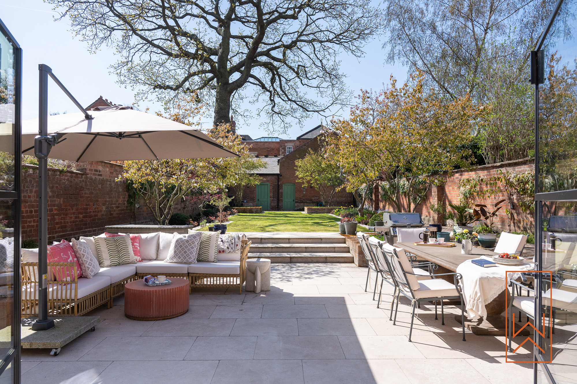 Outdoor dining terrace in a Victorian walled garden with limestone paving and layered planting.