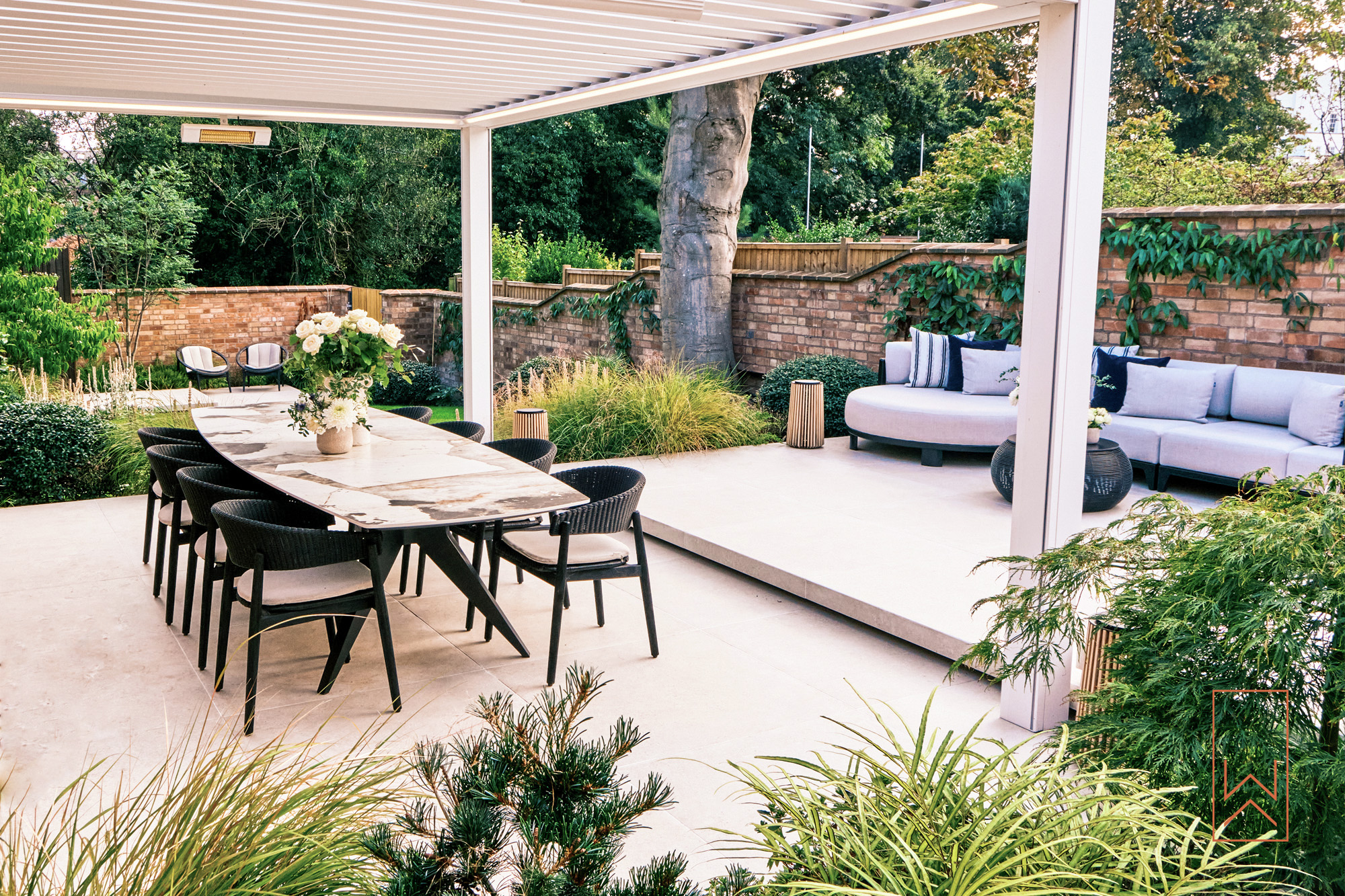 Outdoor dining terrace with pergola in a tiered walled town garden.