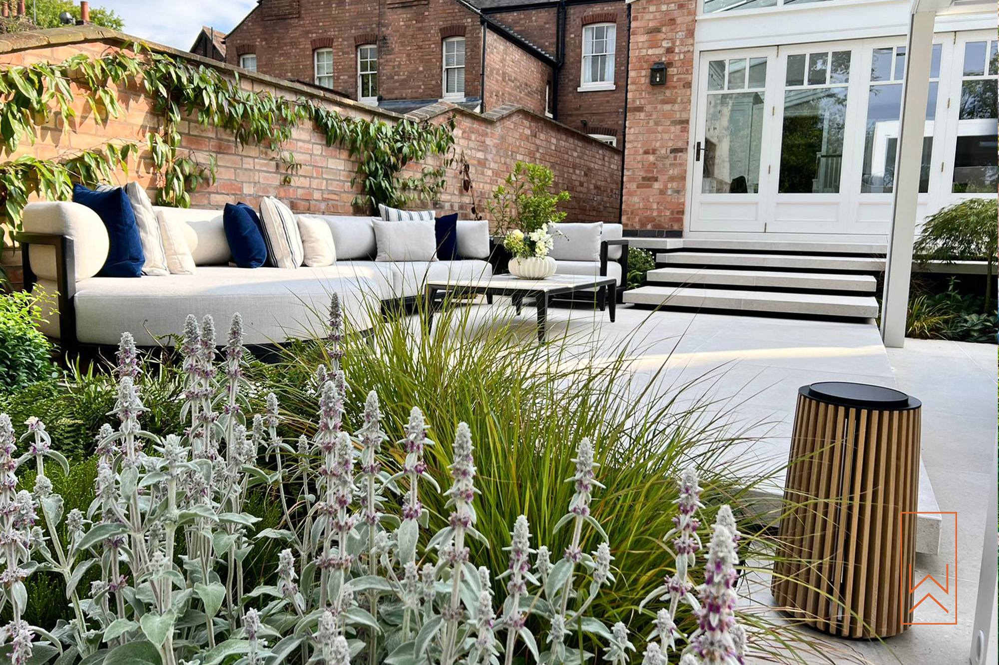Architectural planting and outdoor seating on porcelain terraces in a walled garden.