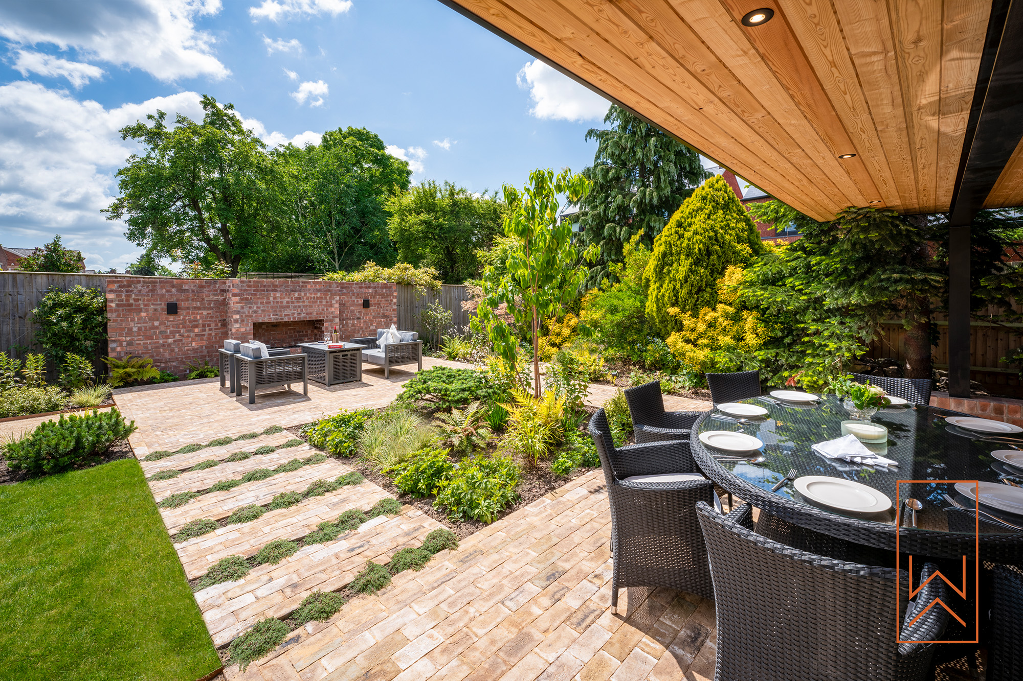 Stepping stone path leading to covered outdoor kitchen in structured garden layout.